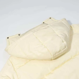 Detail view of cream-colored quilted puffer jacket with detachable hood and snap buttons
