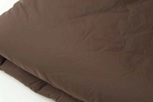 Detailed macro view of dark brown quilted puffer jacket fabric with soft brushed texture