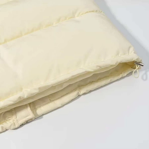 Detail of cream quilted puffer coat featuring adjustable drawstring hem and metal hardware