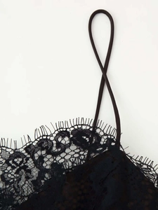 Gros plan sur la bordure en dentelle cil et la fine bretelle d'une robe en satin noir