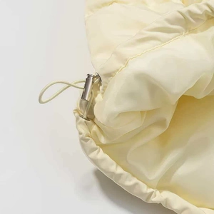 Close-up of cream winter jacket drawstring with polished silver toggle adjuster detail