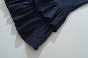 Detailed close-up of the ruffled edges and texture on a navy knit waist dress