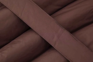 Detail of brown quilted fabric with reinforced webbing and smooth silk-like finish