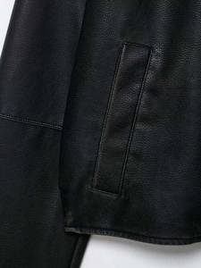 Detail shot of black faux leather jacket showing lychee grain texture and side pocket