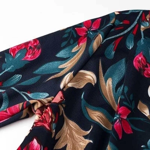 Robe col en V bleu marine avec imprimé floral rouge et détails de feuilles dorées