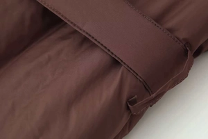 Close-up of brown padded jacket featuring detailed stitching and matching waist belt