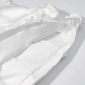 Detailed macro view of white satin fabric with elegant ruffled layers and silk texture