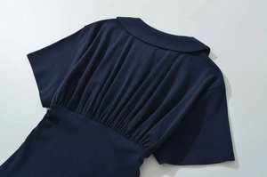 Detail of navy blue dress with Peter Pan collar and intricate pleating on waist