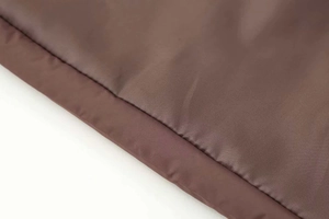 Detail shot of brown quilted fabric with precise stitching for thermal padding