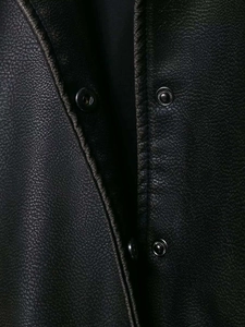 Detailed close-up of black faux leather texture with metallic snap button on jacket