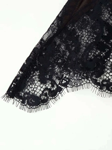 Détail de dentelle de cils noire délicate avec broderie florale sur la robe