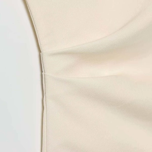 Elegante camicetta beige asimmetrica con pieghe sofisticate e dettagli di cucitura