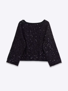 Dettaglio di una giacca di paillettes nere con scollo rotondo e maniche lunghe dal taglio corto