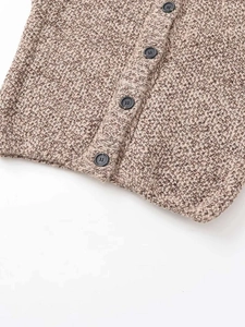Detailed close-up of mixed brown knit fabric and buttons on the sleeveless sweater vest