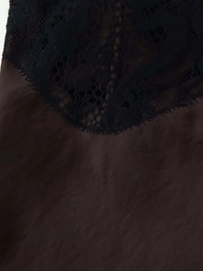 Gros plan sur l'élégante dentelle florale noire cousue sur un tissu en satin marron