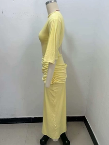 Detail of yellow knit maxi dress featuring stacked waist pleats and open back design