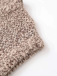 Detailed macro view of the coarse brown and beige knit texture and finished edge quality