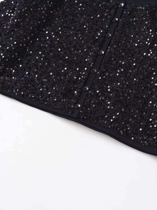 Dettaglio della giacca con paillettes nere con bottoni rotondi e texture brillanti