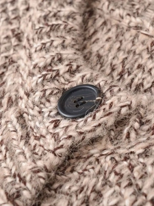 Macro detail of mixed brown knit fabric with fuzzy texture and black resin button