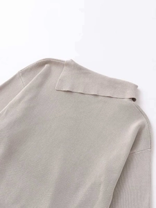 Detailed close-up of light beige knitwear featuring a unique fold-over neck and fine texture