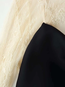 Detailaufnahme der weißen Spitze auf elegantem schwarzem Satin-Kleiderstoff