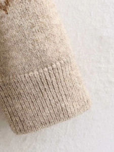 Macro shot of ribbed cuffs on a beige knit cardigan with soft wool texture details