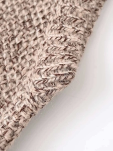 Close-up of knit fabric showing warm brown marl texture and ribbed knit details