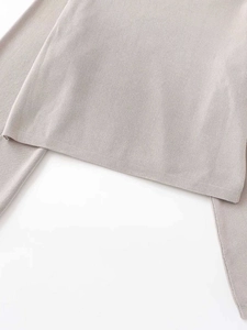 Close-up detail of soft light grey knit sweater showing fine texture and hemline finish