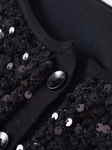 Dettaglio macro della maglia nera con paillettes lucide e bottone in metallo pregiato