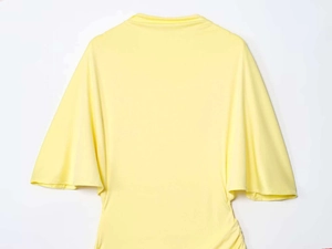 Detail view of light yellow backless top with wide ruffle sleeves and fine knit texture