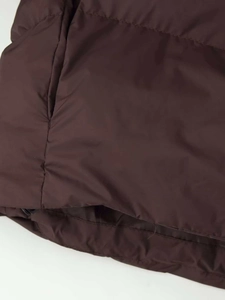 Détail de la doudoune matelassée marron foncé montrant les coutures et le bord de poche