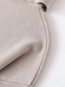 Close-up of soft beige knit fabric showing fine stitching and smooth hem finishing