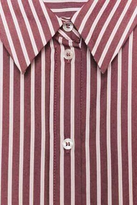 Detail view of the vertical stripes and button-down collar on the burgundy shirt