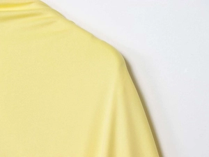 Close-up detail of smooth light yellow fabric showing fine stitching and premium texture