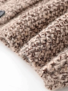 Detail of warm brown marl knitwear texture showing thick yarn and black button