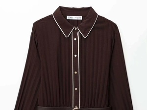 Détail d'une robe midi plissée chocolat avec bordure blanche et ceinture élégante