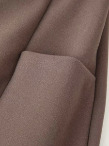 Detailed close-up of brown wool fabric texture and professional pocket stitching on coat