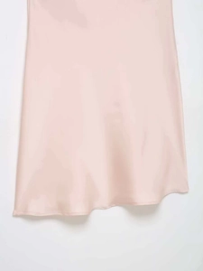 Gros plan sur l'ourlet d'une robe en satin rose clair, texture lisse et couture fine