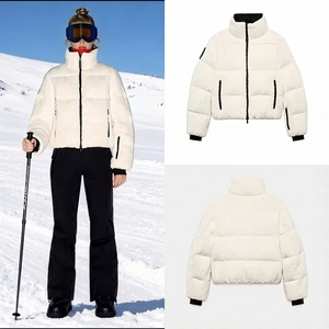 Detailed view of white padded ski jacket with contrasting black zippers and high collar
