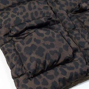 Detailed macro shot of dark leopard print quilted puffer jacket with subtle glossy finish