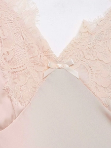 Gros plan sur une nuisette en satin rose avec dentelle délicate et petit nœud