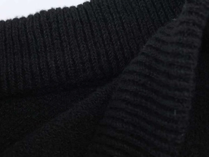 Gros plan détaillé sur la texture en maille côtelée noire et la matière en laine mélangée