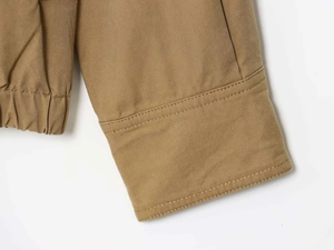 Close-up of canvas bomber jacket showing double stitching details and elastic hem