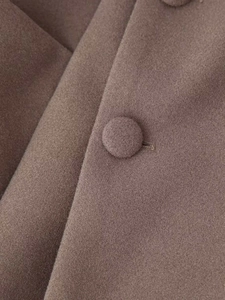 Detail of wool coat fabric featuring a matching covered button and soft texture