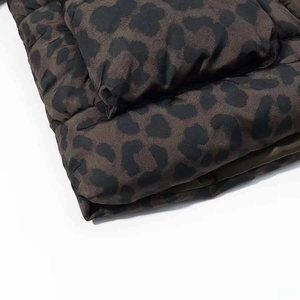 Detailed macro view of leopard print puffer jacket fabric with quilted texture and stitching