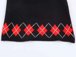 Detailopname van winterse gebreide set met rood en wit ruitpatroon op zwarte stof
