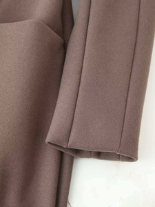Close-up of premium brown wool blend fabric and detailed stitching on the sleeve cuff