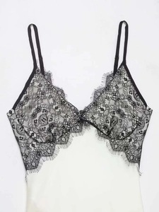 Détail d'une nuisette blanche avec dentelle de cils noire, broderie florale et bretelles