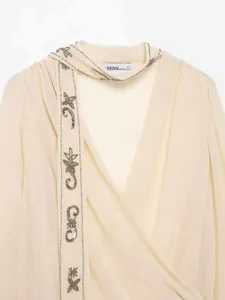 Détail de chemisier beige en mousseline avec broderies d'étoiles argentées
