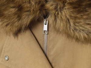 Close-up of metal zipper, snap button, and premium faux fur collar on bomber jacket